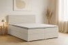 Stilvoll eingerichtetes Schlafzimmer mit einem modernen Boxspringbett aus beigem Cord-Stoff.