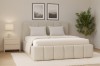 Beige Polsterbett Megan in hellem Schlafzimmer mit gemütlicher Atmosphäre und Zimmerpflanze.