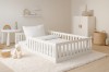 Gemütliches Montessori-Bett in Weiß im hell eingerichteten Kinderzimmer mit Teppich und Spielzeug.