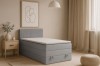 Lichtblauw boxspringbed met geribbeld hoofdbord en bedbak in een moderne slaapkamer.
