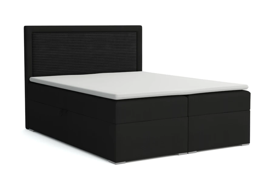 Klassisches Boxspringbett in Schwarz mit geripptem Kopfteil und weißem Topper auf weißem Hintergrund.