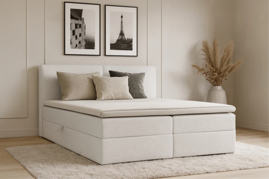 Modernes weißes Boxspringbett in hellem Schlafzimmer mit Kissen und Teppich.
