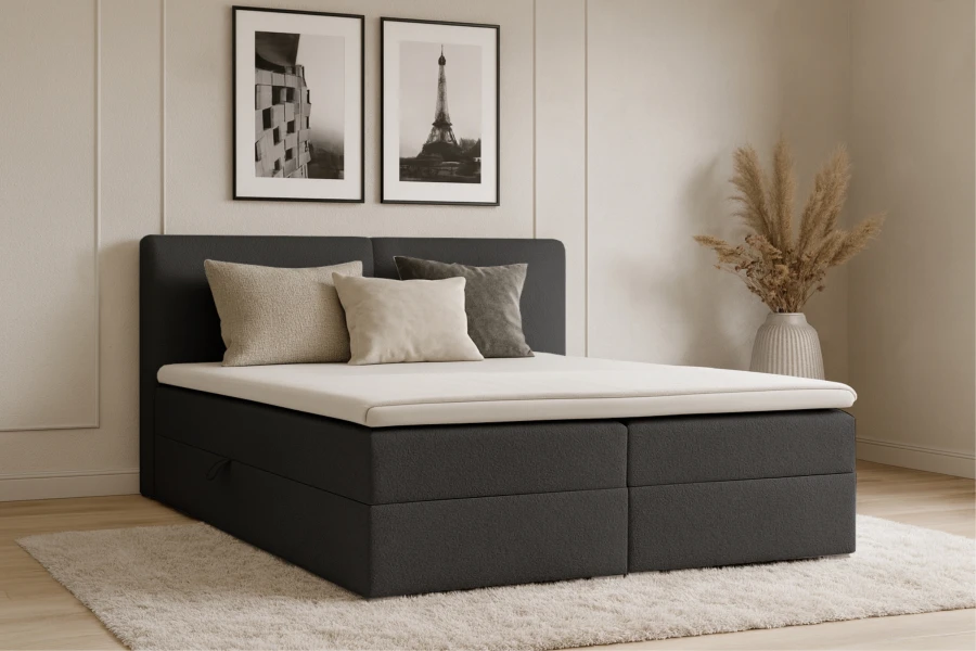 Anthrazitfarbenes Boxspringbett im Schlafzimmer-Ambiente mit Wandbildern.