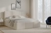 Modernes beiges Polsterbett im hellen Schlafzimmer mit minimalistischer Dekoration.