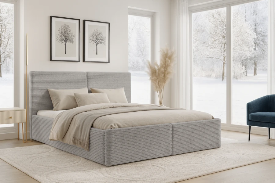 Modernes hellgraues Boxspringbett in gemütlicher Schlafzimmer-Atmosphäre mit Winterpanorama.