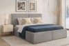 Graues Polsterbett im Schlafzimmer mit blauer Tagesdecke und elegantem Nachttisch.