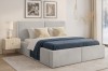 Light grey upholstered bed in a bedroom set with blue blanket and stylish white bedside table.