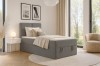 Dunkelgraues Boxspringbett in einem geschmackvoll eingerichteten Schlafzimmer mit großer Fensterfront.