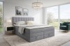 Stilvoll eingerichtetes Schlafzimmer mit dem hellgrauen Boxspringbett Verno, Teppich und gemütlichem Sessel.