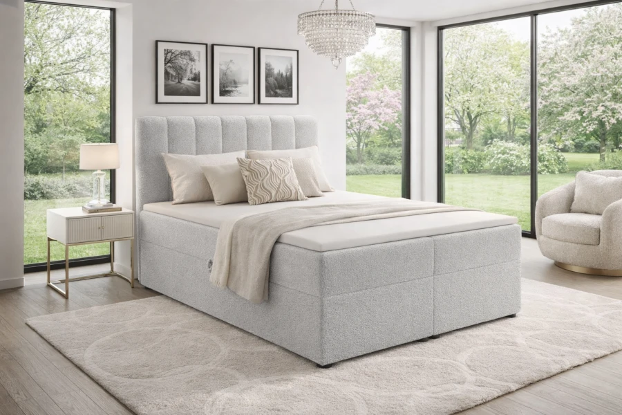 Modernes hellgraues Boxspringbett in einem hellen Schlafzimmer mit Gartenblick.