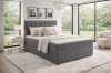 Graues Boxspringbett mit hohem Kopfteil in modernem, lichtdurchflutetem Raum.