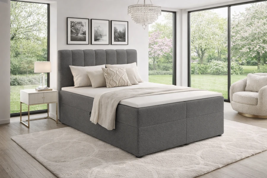 Graues Boxspringbett mit hohem Kopfteil in modernem, lichtdurchflutetem Raum.