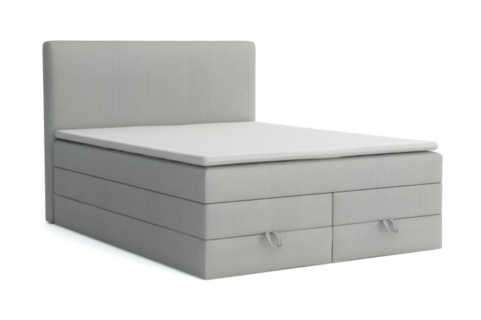 Hellgraues Boxspringbett mit weißem Topper auf weißem Hintergrund freigestellt.
