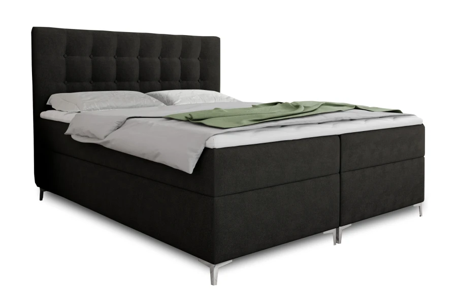 Dunkelgraues Boxspringbett mit Knopfsteppung am Kopfteil und grüner Decke auf weißem Hintergrund.