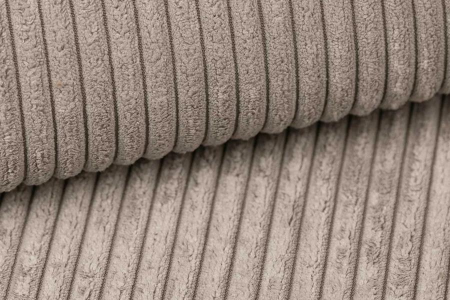Nahaufnahme der weichen Textur des beigen Cord-Stoffbezugs für Polstermöbel.