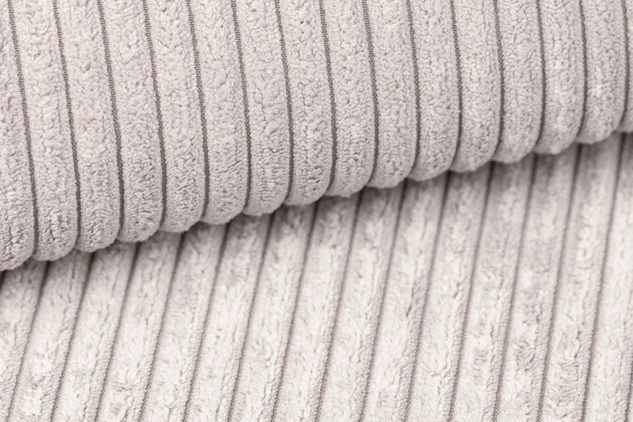 Close-up van de beige corduroy stofstructuur van een modern gestoffeerd bed.