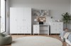 Helles Kinderzimmer mit weißen Möbeln, großem Fenster, rundem Teppich und grünem Sitzsack.