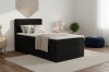 Stilvolles Schlafzimmer mit schwarzem Einzelbett, dekorativen Kissen und Teppich.