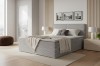 Graues Boxspringbett in minimalistischem Schlafzimmer mit Teppich.