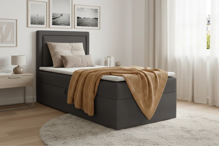 Anthrazitfarbenes Boxspringbett mit Bettkasten und gelber Wolldecke in modernem Design.