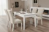 Moderne witte eettafel met 4 beige fluwelen stoelen in een stijlvolle woonkamer met open haard.