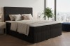 Luxuriöses Boxspringbett in Anthrazit mit hochwertigem Cord-Bezug und weichen Kissen.