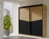 Schlafzimmer-Ambiente mit dem Arno Schiebetürenschrank in Eiche und Schwarz vor einem Fenster.