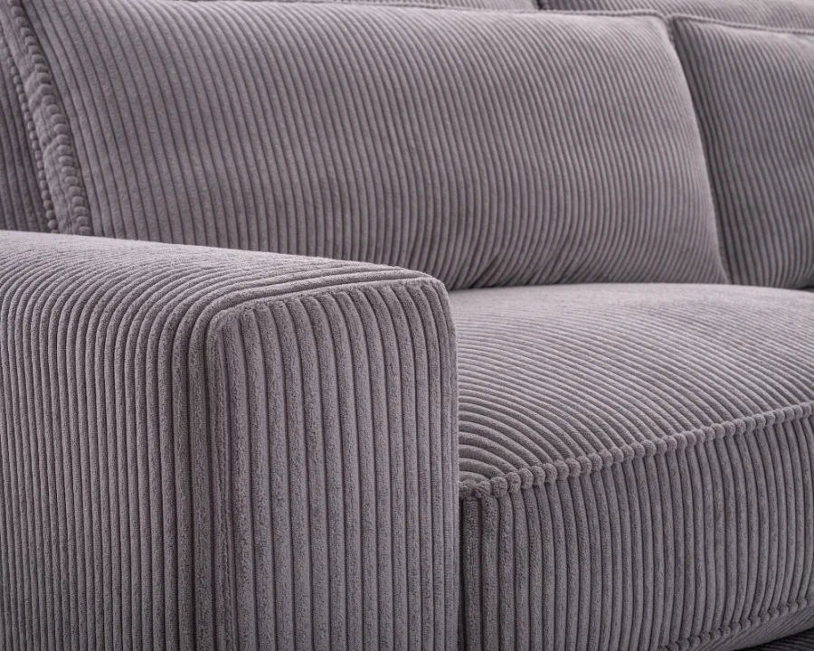 Nahaufnahme der hochwertigen Cord-Struktur und präzisen Nähte eines grauen Sofas.