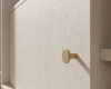 Detailansicht eines runden Goldgriffs an einer hellen Georgia Schranktür.