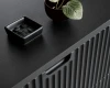 Nahaufnahme der schwarzen Holzoberfläche und der geriffelten Front eines Sideboards.