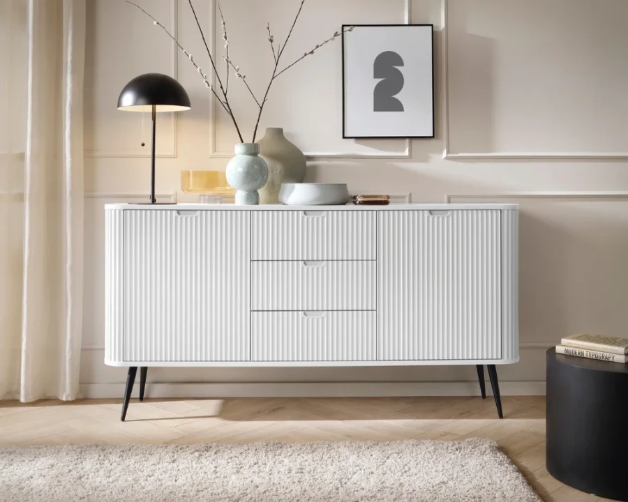 Weißes Sideboard mit geriffelter Front und schwarzen Beinen im modernen Wohnzimmer.