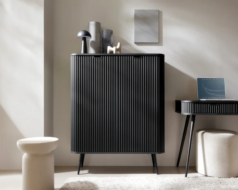 Schwarzer Design-Schrank mit vertikalen Lamellen in einem minimalistisch eingerichteten Wohnzimmer.
