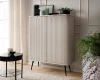 Modernes beiges Highboard mit Rillenstruktur und schwarzen Beinen in wohnlicher Umgebung.
