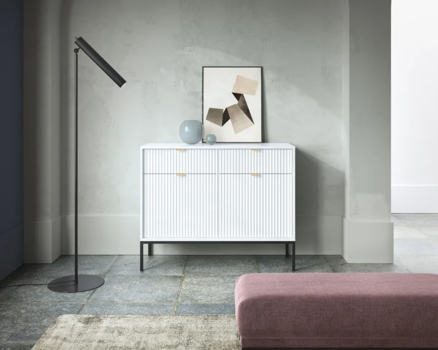 Stilvolles Wohnzimmer-Ambiente mit weißem Sideboard, schwarzer Stehlampe und moderner Wanddekoration.