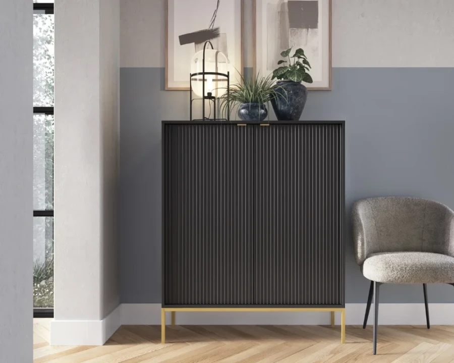 Schwarzes Highboard mit Rillenoptik und goldenen Metallfüßen in einem modern eingerichteten Raum.