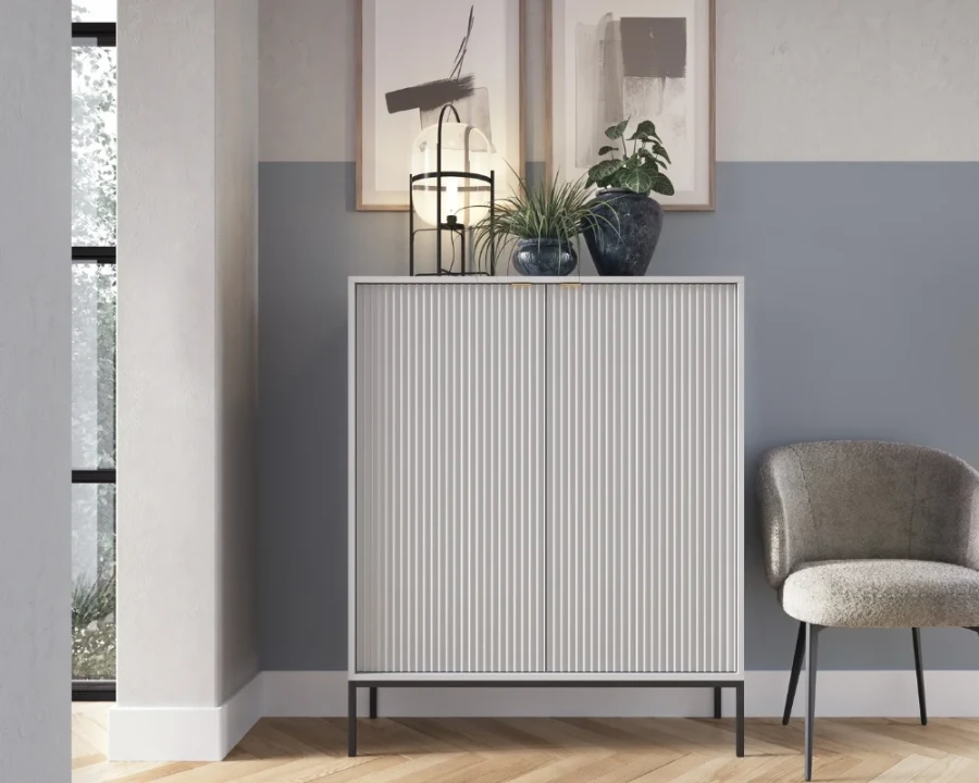 Wohnzimmer-Dekoration mit weißem Design-Schrank, Zimmerpflanzen und Sessel.