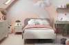 Modernes Kinderzimmer in Rosa und Weiß mit gemütlichem Einzelbett, Wolkendekoration und Schreibtisch.