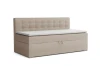 Beiges Boxspringbett mit Knopfheftung am Kopfteil und integriertem Bettkasten.