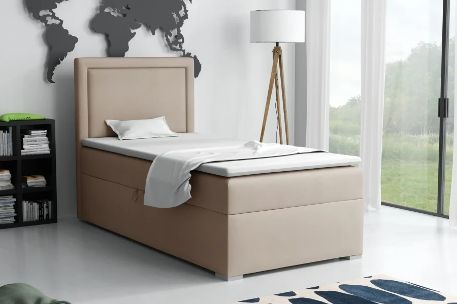 Beiges Boxspringbett im hellen Schlafzimmer-Ambiente mit Stehlampe und Bücherregal.