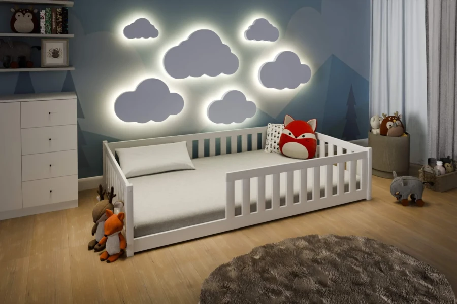 Weißes Kinderbett mit Rausfallschutz in gemütlichem Kinderzimmer mit leuchtenden Wolkenlampen.