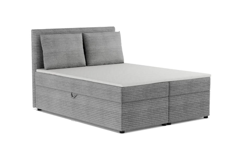 Graues Boxspringbett aus Breitcord mit zwei passenden Kissen vor weißem Hintergrund.