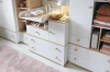 Wickelkommode Oktavia in Weiß mit Holzgriffen und Wickelaufsatz im eingerichteten Babyzimmer.