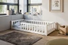 Weißes Kinderbett in Bodennähe mit Rausfallschutz in einem gemütlich eingerichteten Kinderzimmer.