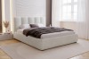 Bedroom with white bouclé upholstered bed, rug and bright window background.