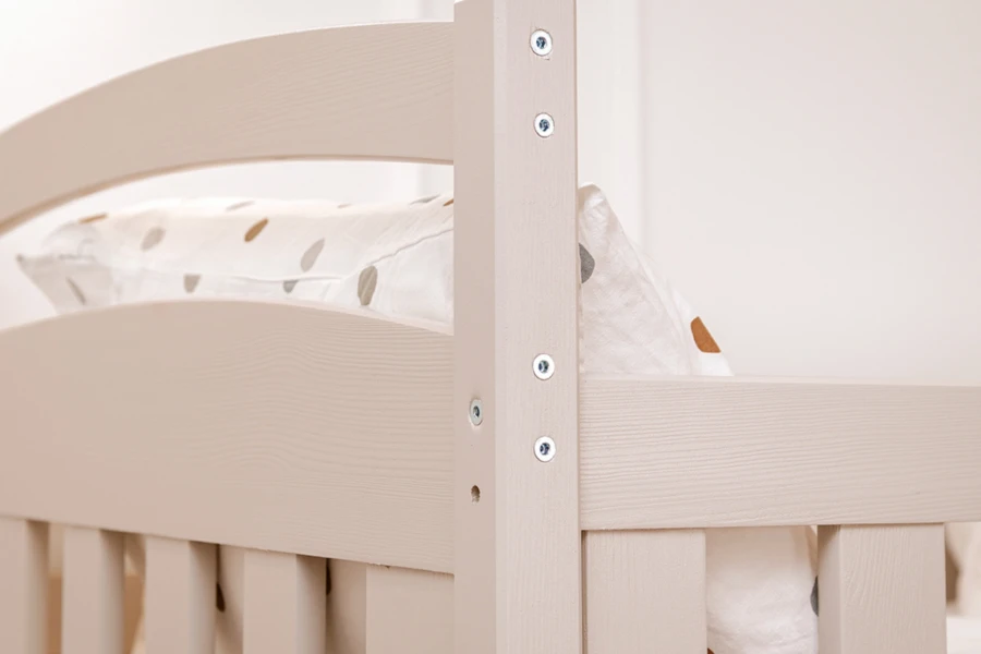 Close-up of a white wooden bunk bed with visible screw connections.