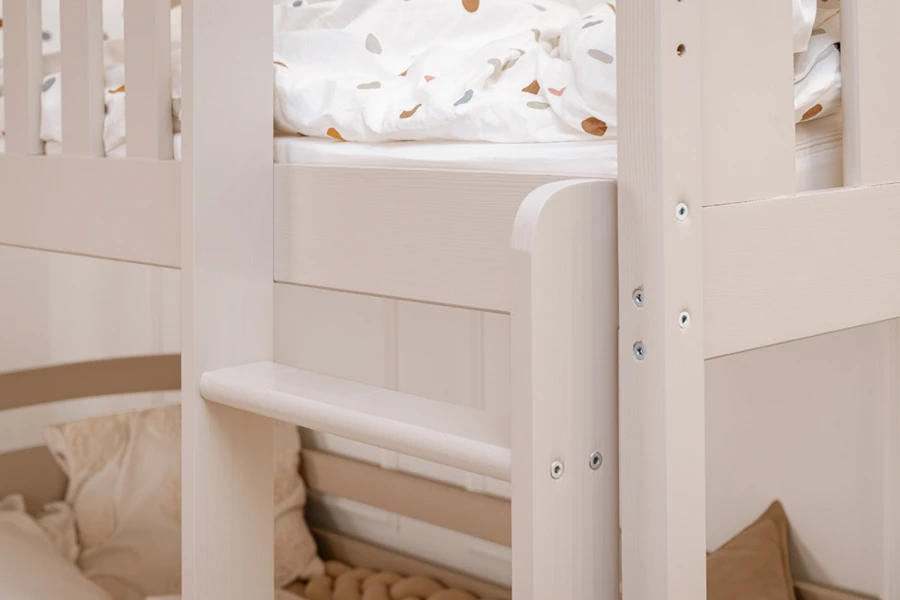 Detailopname van de ladder en de uitvalbeveiliging van een wit kinder-stapelbed.
