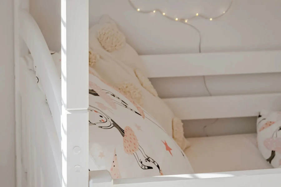Bovenste stapelbed met witte houten spijlen en decoratieve kussens
