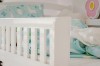 Weißer Rausfallschutz am Kinderbett mit blauer Lama-Bettwäsche in der Nahaufnahme.