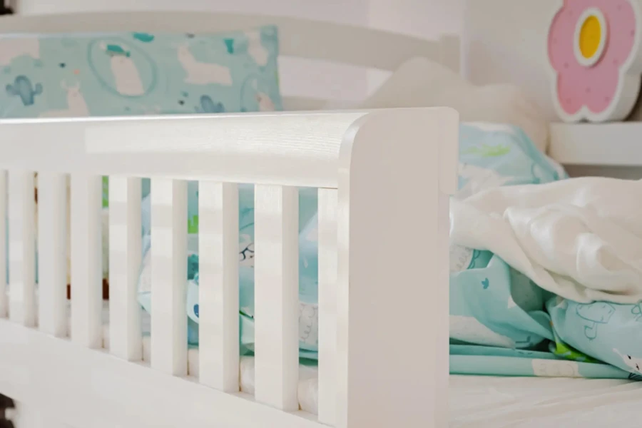 Weißer Rausfallschutz am Kinderbett mit blauer Lama-Bettwäsche in der Nahaufnahme.