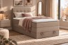 Gemütliches beiges Boxspringbett in warmem Schlafzimmer-Ambiente mit Deko.